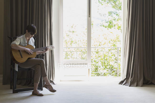 Женщина играет на гитаре в помещении — стоковое фото