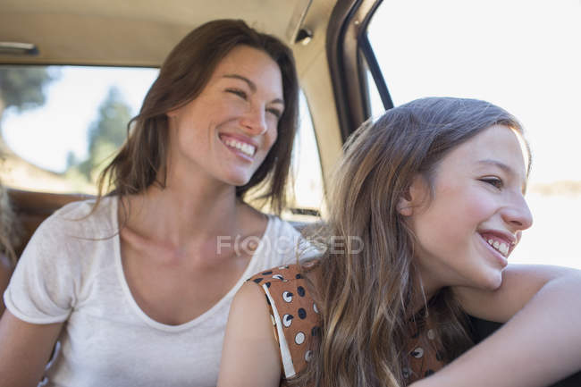 Щасливі красиві сестри верхи на задньому сидінні автомобіля разом — стокове фото