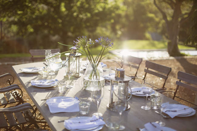 Bouquet e luogo impostazioni sul tranquillo tavolo patio — Foto stock