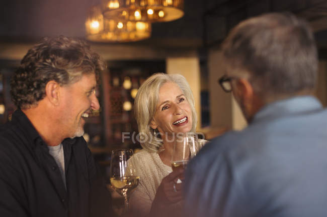 Amigos bebendo vinho branco e conversando no restaurante — Fotografia de Stock