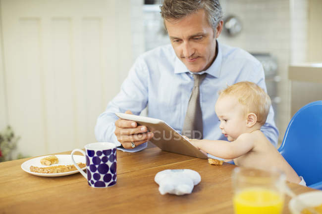 Padre y bebé usando tableta digital - foto de stock