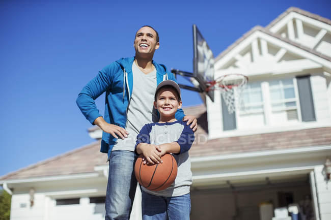 Отец и сын с баскетболом у дома — стоковое фото