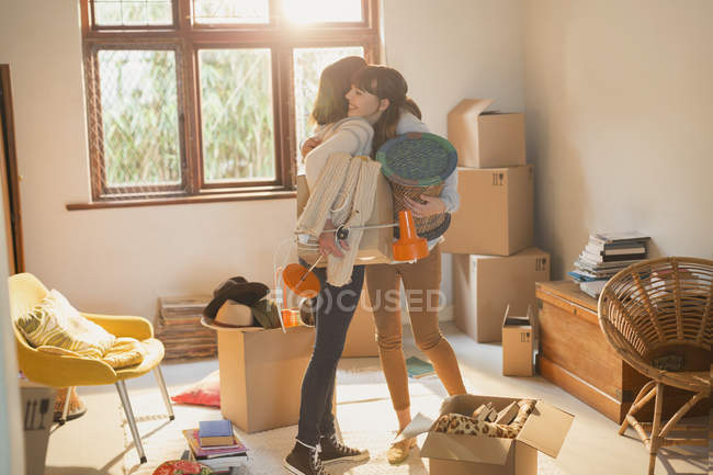Madre e figlia abbracciare scatole disimballaggio in appartamento — Foto stock