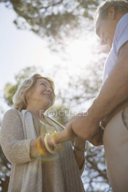 Senior couple holding hands under trees — Stock Photo