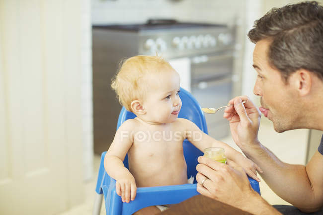 Pai alimentando bebê em cadeira alta — Fotografia de Stock