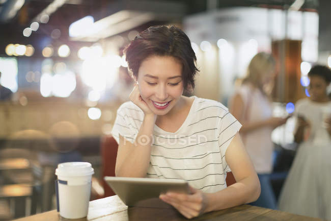 Jovem mulher usando tablet digital e beber café no café — Fotografia de Stock