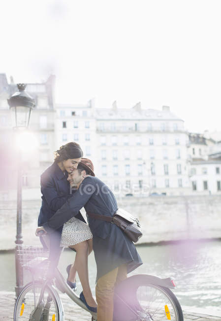 Couple hugging on bicycle along Seine River, Paris, France — Stock Photo