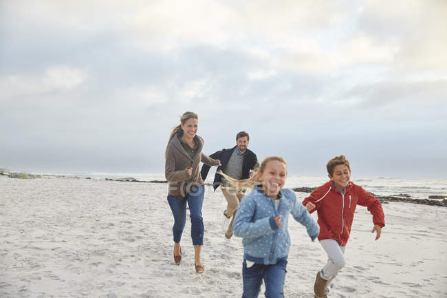 Família brincalhão correndo na praia de inverno — Fotografia de Stock