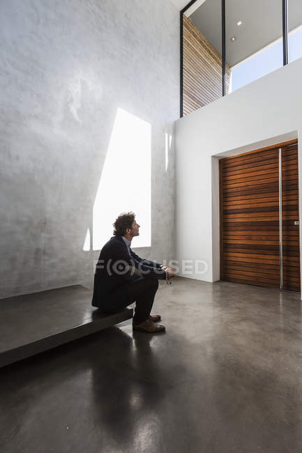 Pensive businessman looking up at window in sunny modern foyer — Stock Photo