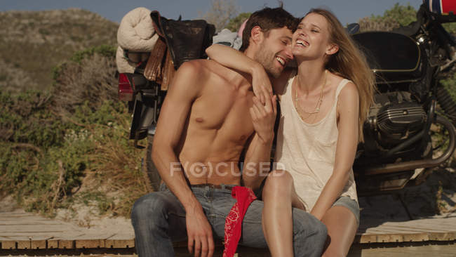 Любящие молодые пары обнимаются и смеются над мотоциклом — стоковое фото