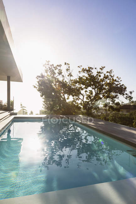 Ruhige, sonnige Reflexion des Baumes über dem Swimmingpool auf der luxuriösen Terrasse — Stockfoto
