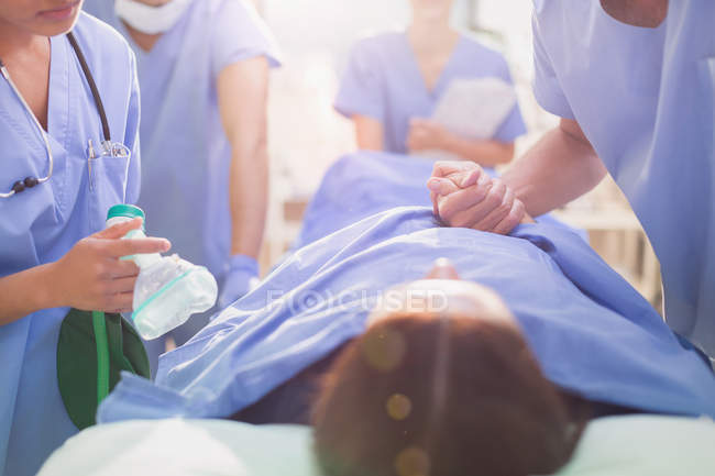 Surgeon holding hand of patient on stretcher — Stock Photo