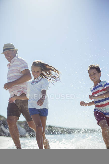 Famille courant dans l'eau sur la plage — Photo de stock