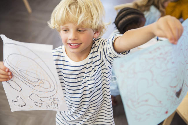 Estudiante mostrando dibujos en el aula - foto de stock