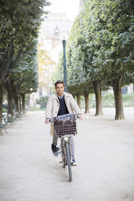 Businessman riding bike in park, Paris, Francia - foto de stock