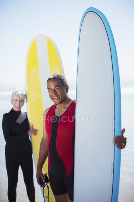 Porträt eines älteren multiethnischen Paares mit Surfbrettern — Stockfoto