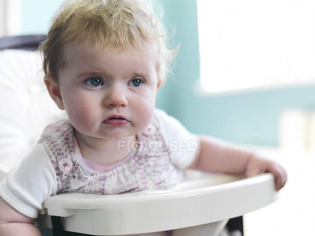 Girl sitting in high chair — Stock Photo
