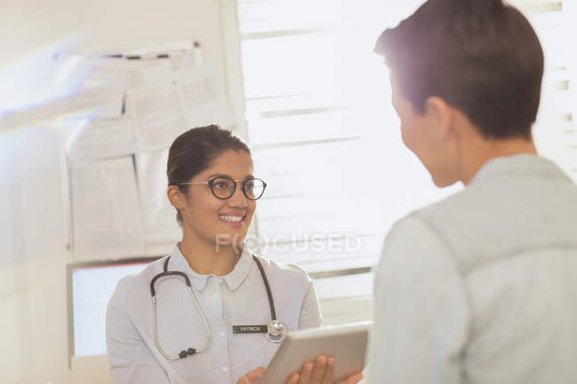Médica com comprimido digital a falar com a doente na sala de exame — Fotografia de Stock