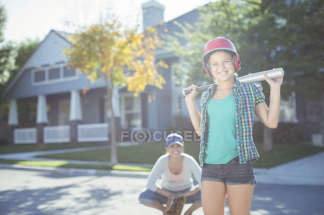 Portrait of mother and daughter playing baseball in street — Stock Photo
