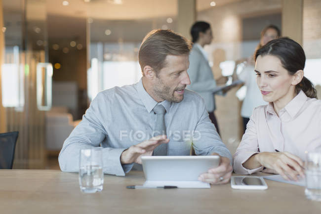 Empresario y mujer de negocios usando tableta digital, hablando en la reunión de la sala de conferencias - foto de stock