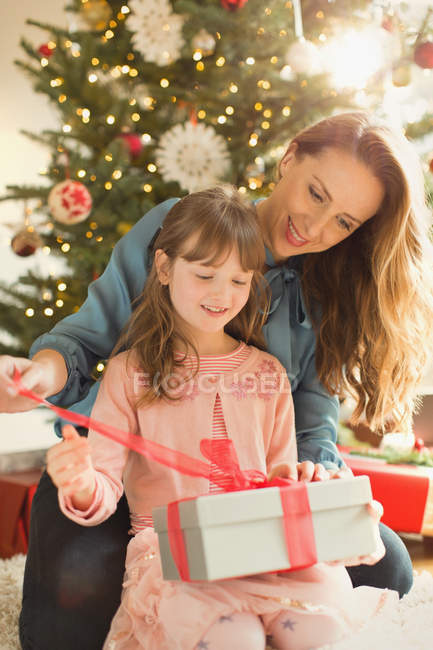 Мати допомагає дочці відкрити різдвяний подарунок — стокове фото