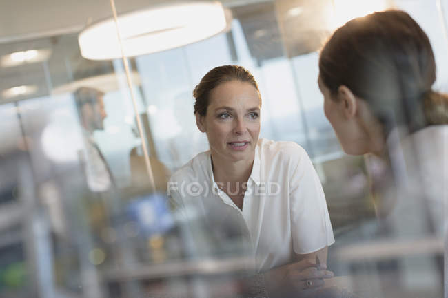 Mujeres de negocios felices hablando en la oficina moderna - foto de stock