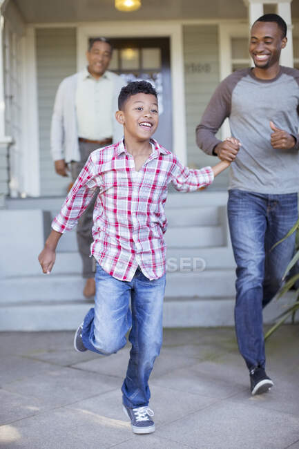 Отец и сын держатся за руки и выбегают из дома — стоковое фото
