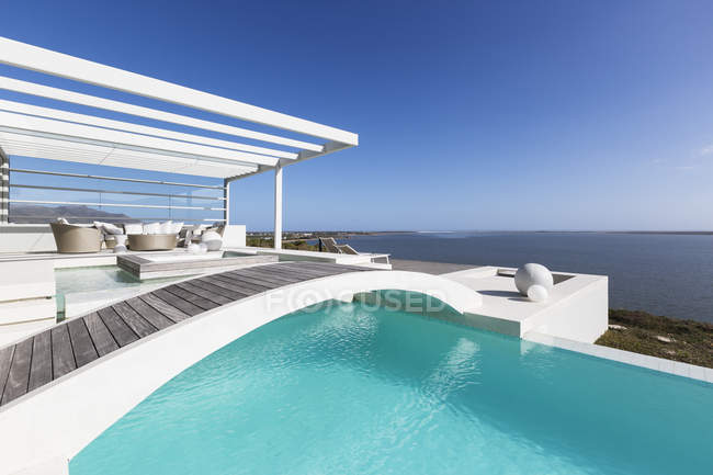 Сонячний спокійний будинок вітрина зовнішній нескінченний басейн з видом на океан під блакитним небом — стокове фото