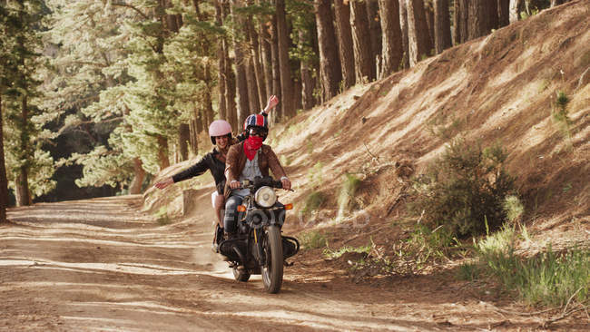 Богатая молодая женщина едет на мотоцикле по грунтовой дороге в лесу — стоковое фото