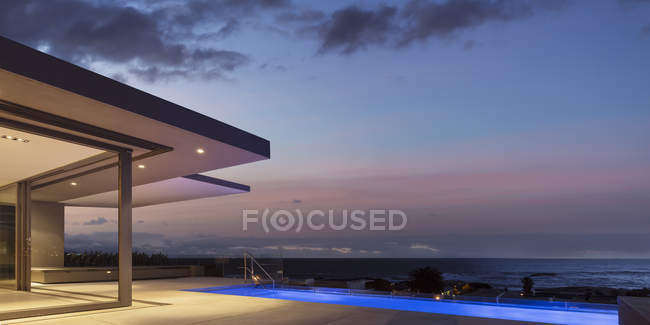 Tranquillo cielo crepuscolo sopra illuminato casa vetrina patio esterno con piscina giro — Foto stock