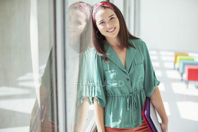 Portrait of casual businesswoman leaning against window in sunny office — Stock Photo