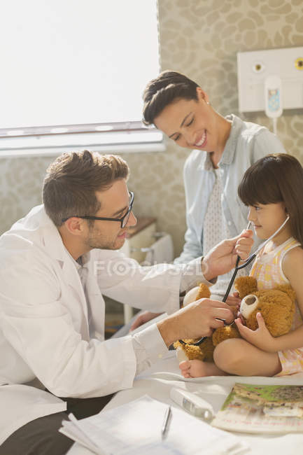 Male doctor showing stethoscope to girl patient in hospital room — Stock Photo