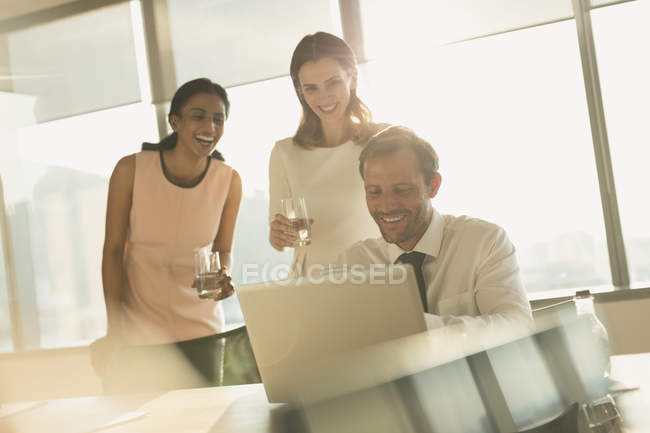 Uomini d'affari che lavorano al computer portatile in ufficio soleggiato — Foto stock