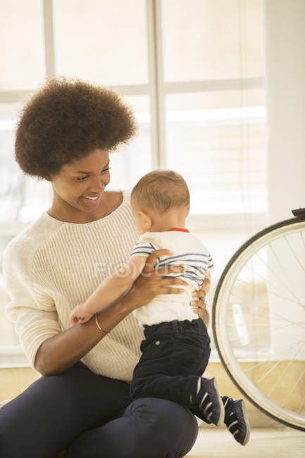 Mother holding baby boy on floor at home — Stock Photo