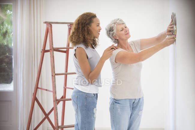 Dos mujeres decidiendo el color de la pared juntas - foto de stock