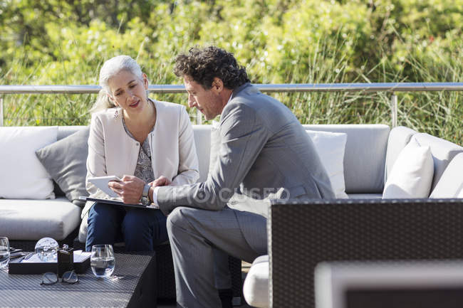 Homme d'affaires et femme d'affaires utilisant une tablette numérique sur un canapé patio balcon — Photo de stock