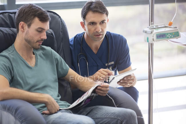 Médecin tenant une tablette numérique, parlant au patient subissant un traitement médical à l'hôpital — Photo de stock