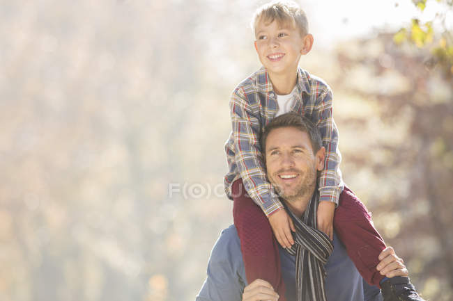 Sonriente padre llevando hijo en hombros al aire libre - foto de stock