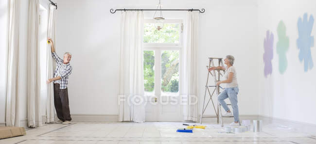 Älteres Paar hängt Gardinen zusammen — Stockfoto