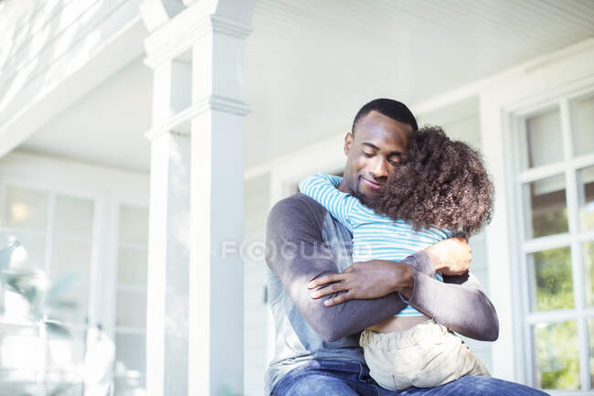 Отец обнимает дочь на крыльце — стоковое фото