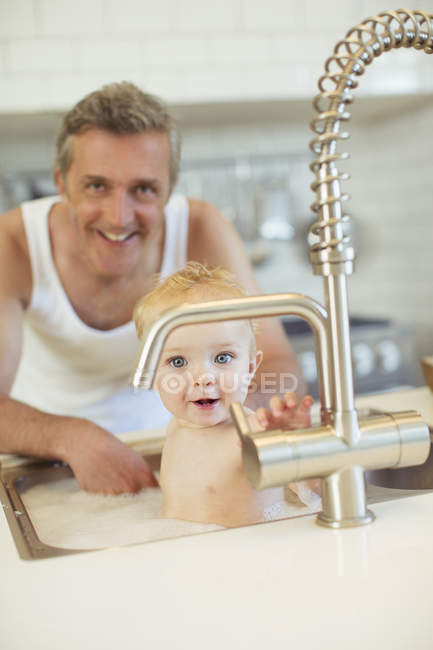 Vater badet Baby in Küchenspüle — Stockfoto