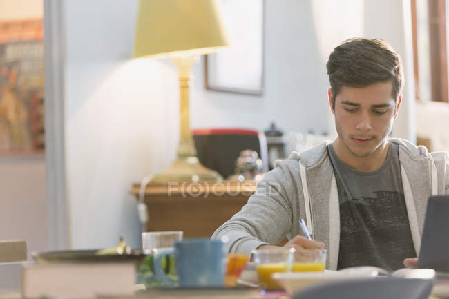 Молодой человек студент колледжа учится за завтраком — стоковое фото