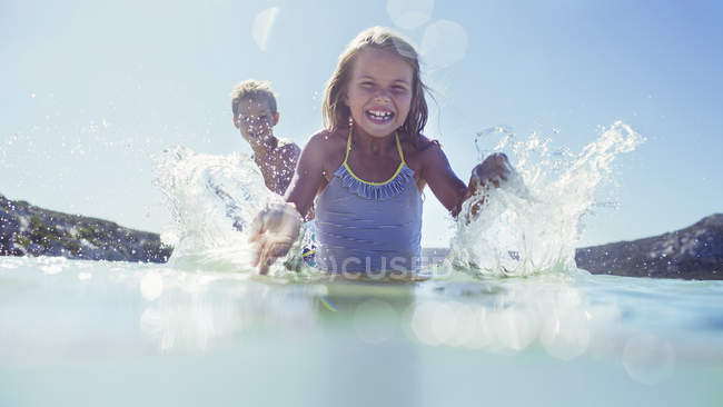 Молодая девушка и брат плескаются в воде — стоковое фото