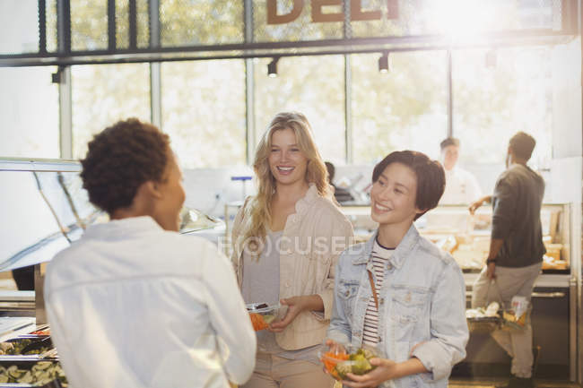 Mujeres jóvenes amigas en el bar de ensaladas en el mercado de comestibles - foto de stock