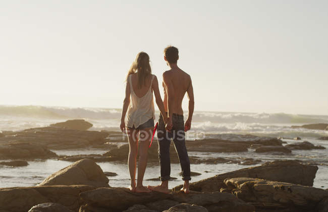 Young couple holding hands and looking at ocean view — Stock Photo