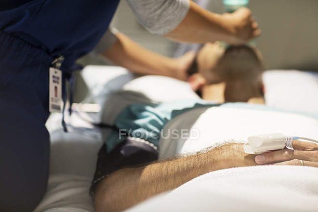 Doctor holding oxygen mask over male patient's mouth in intensive care unit — Stock Photo