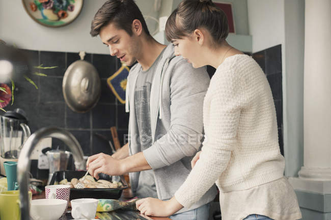 Casal jovem cozinhar na cozinha juntos — Fotografia de Stock
