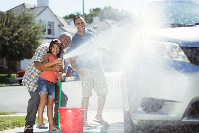 Multi-generation family washing car in driveway — Stock Photo