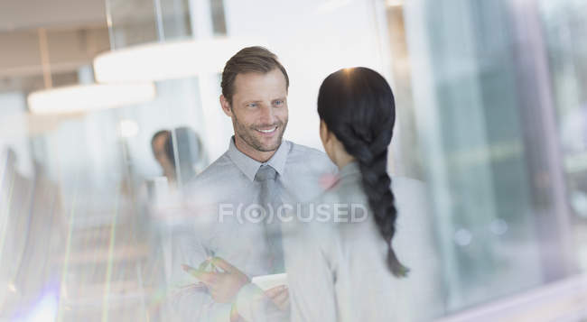 Empresário sorridente conversando com colega no escritório — Fotografia de Stock