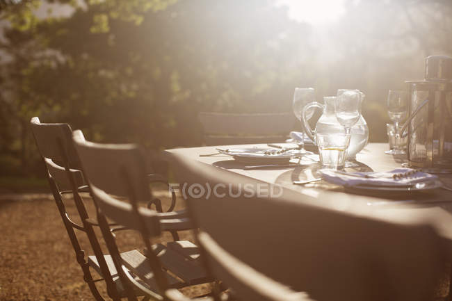 Coloque as configurações na mesa do pátio tranquilo ensolarado — Fotografia de Stock